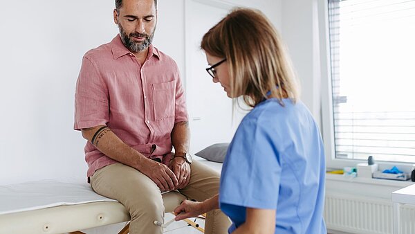 Ein Ärztin führt eine eingehende neurologische Untersuchung nach GOÄ-Ziffer 800 an einem Patienten durch, der auf einer Liege sitzt.