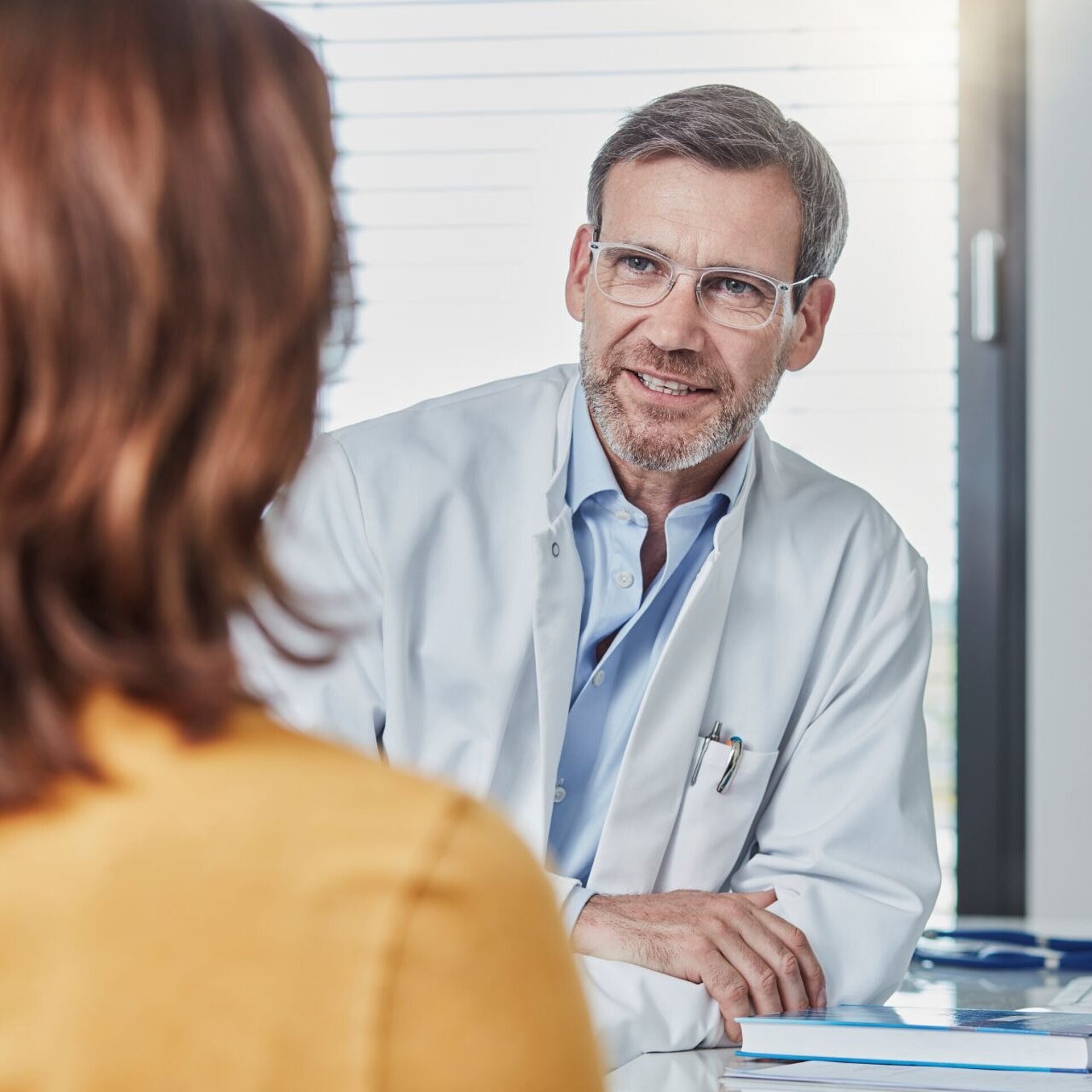 Ein Hausarzt in seiner Praxis im Gespräch mit seiner Patientin; Symbolbild für die GOÄ-Privatabrechnung in der Inneren/Allgemeinmedizin