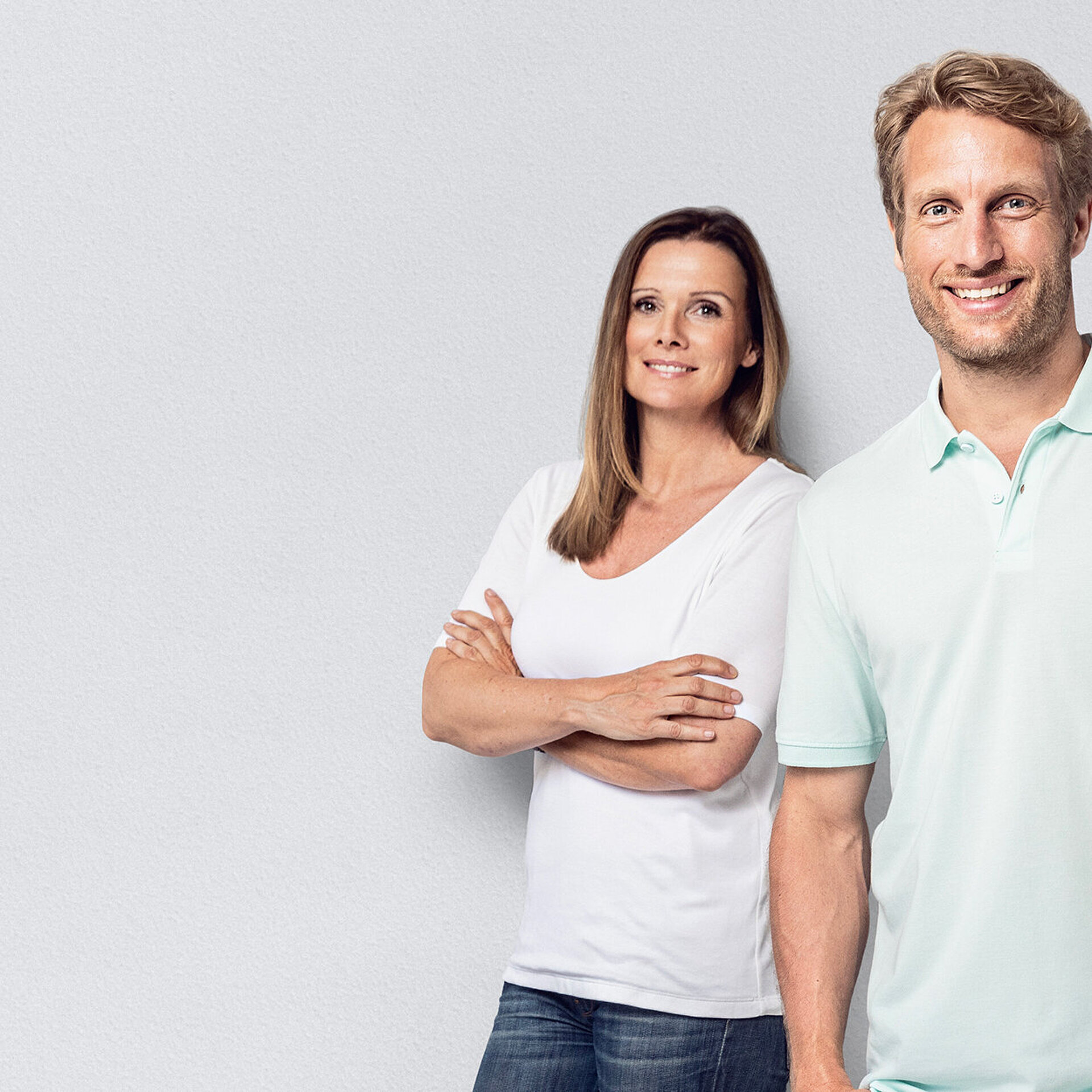 Eine Internistin und ein Allgemeinmediziner stehen lächelnd nebeneinander.