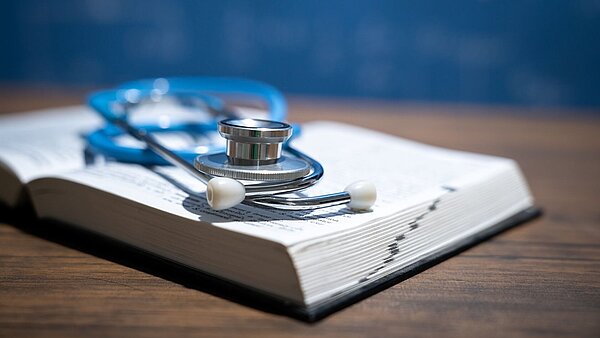 Ein Stethoskop liegt auf einem geöffneten Buch