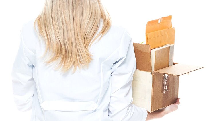 Eine gekündigte Ärztin hält einen Karton in ihrer Hand