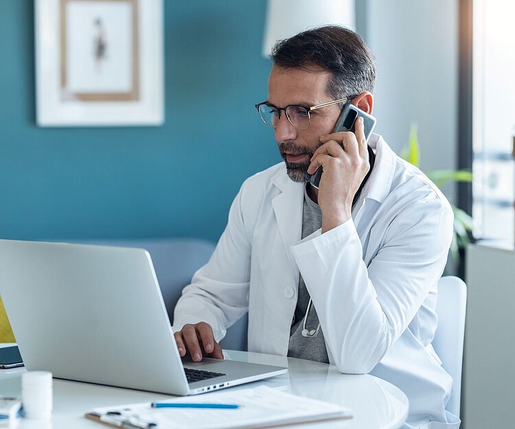 Ein Arzt telefoniert mit einem anderen Arzt, um eine Diagnose und/oder Therapie eines Patienten zu erörtern; Symbolbild für das Konsil nach GOÄ-Ziffer 60